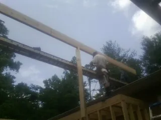 Carpenter setting a ridge beam over a new addition frame — Ice Dam Removal by Roofing Brothers in Breesport