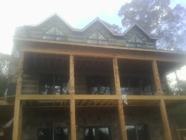 Dormers and porch framing on a large log home under construction — Roof Coating work by our crew in Breesport