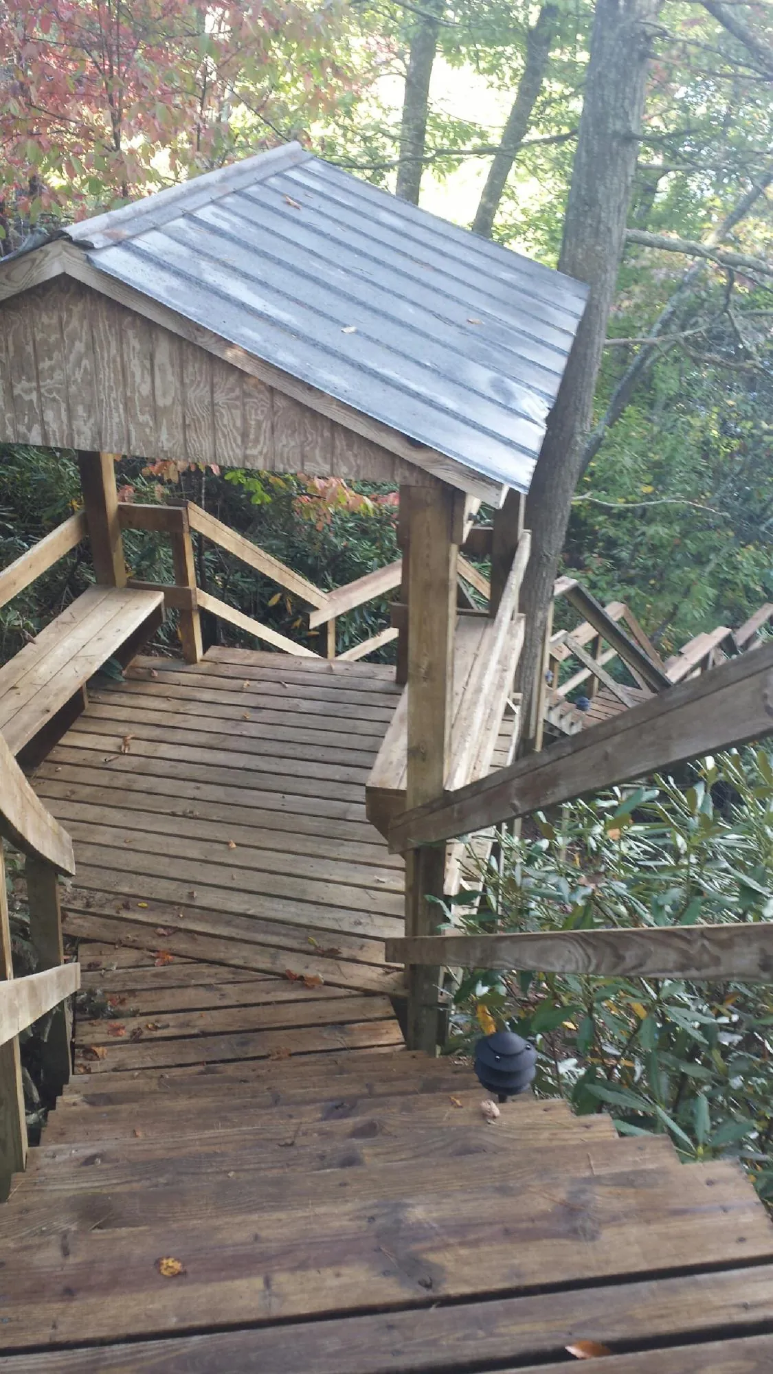 Metal roofed shelter over wooden steps on a wooded walkway — Skylight Repair & Installation work by our crew in Breesport
