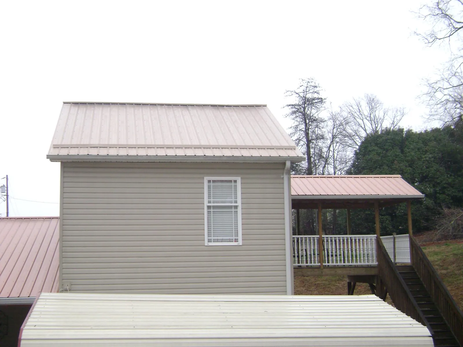 Tan metal roofs on a two story addition and attached porch, from a Roof Replacement job in Breesport