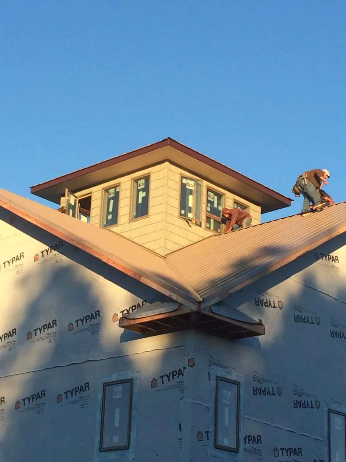 Roofers working around a rooftop cupola on a new metal roof at sunset — Roof Waterproofing in Breesport by Roofing Brothers